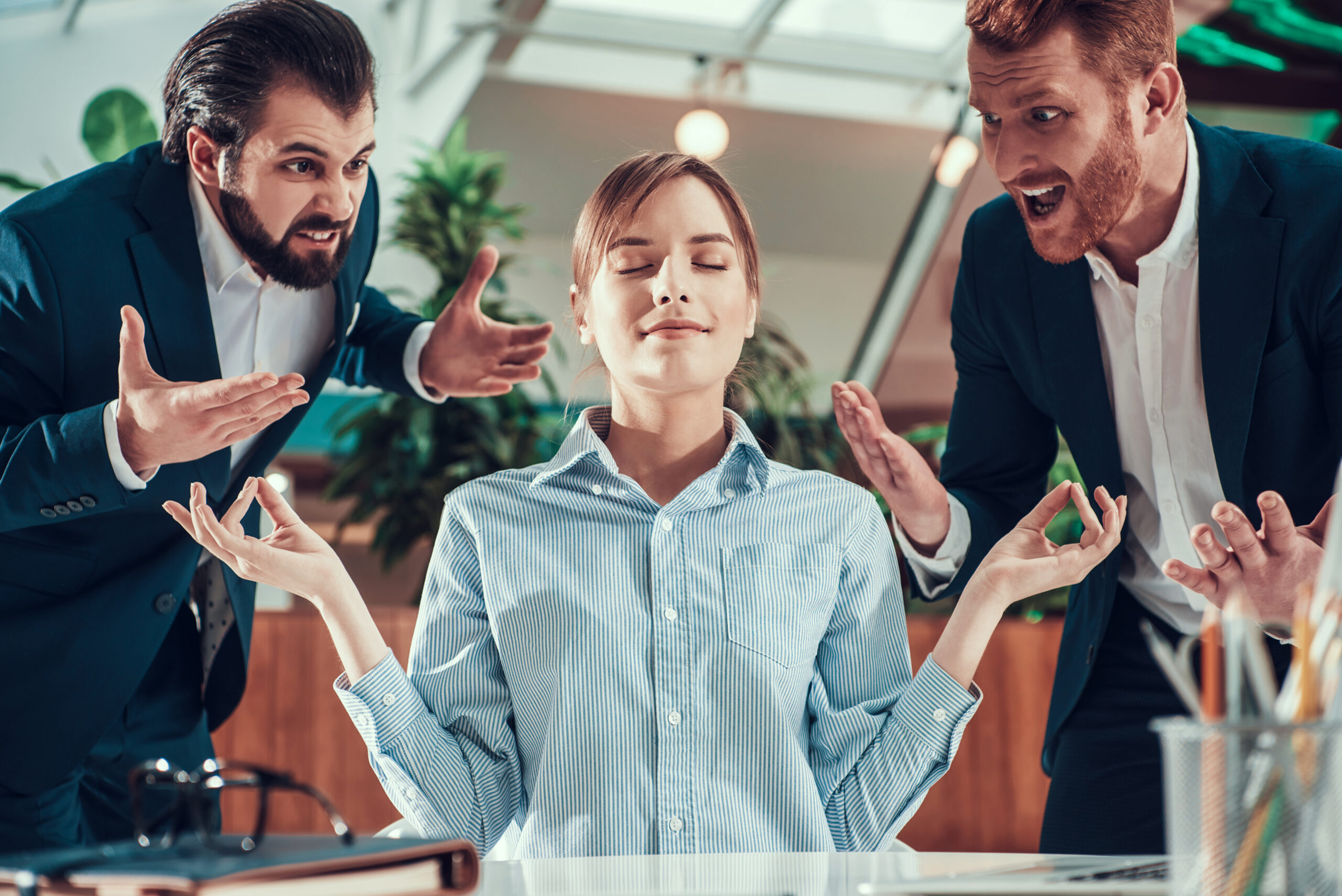 People shout at meditating worker in suit in office.